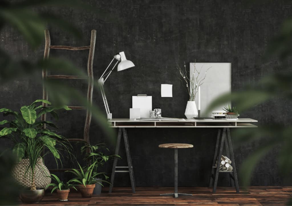 A white artists desk surrounded by houseplants